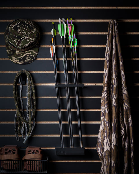 Slatwall quiver holding 3 dozen arrows in organized workshop setting